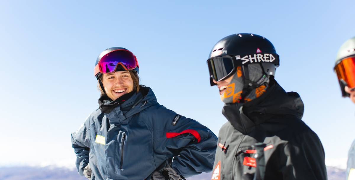 Two people in ski gear against a blue sky